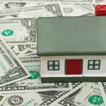 Main-Photo-on-Top_10456818-mini-house-on-us-dollars-abstract-background