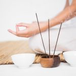 Fit woman meditating on bamboo mat on white background