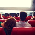 happy couple watching movie in theater or cinema