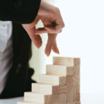 partial view of woman walking with fingers on wooden blocks symb