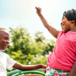 African kids looking at each other raising hands.
