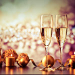 two champagne glasses against holiday lights and fireworks – new