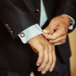 The man fastens the cuffs of his shirt.