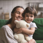 Smiling single young mum embracing little daughter