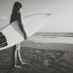 woman with surfboard on beach