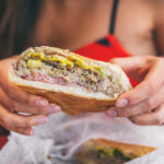 Cuban sandwich closeup woman holding local food at typical cafe outside. Pressed cuban bread with roasted pork, salami sausage, swiss cheese, mustard, typical cuba dish.